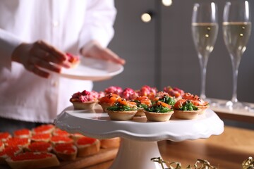 Buffet menu. Woman taking tasty tartlet from table, selective focus