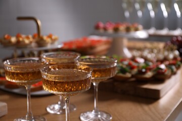 Buffet menu. Glasses of sparkling wine and tasty appetizers on table, closeup