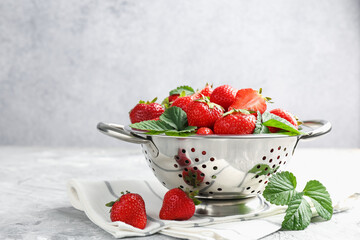 Delicious ripe strawberries and green leaves on grey table, closeup. Space for text