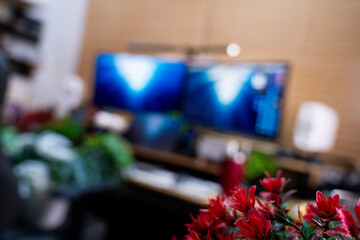 A detailed view of a modern and organized workspace, showcasing dual monitors displaying dynamic blue visuals, complemented by indoor plants and a collection of mechanical keyboards.