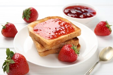 Toasts with tasty strawberry jam and fresh berries on white wooden table, closeup