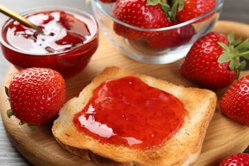 Toast with tasty homemade strawberry jam and berries on wooden table, closeup
