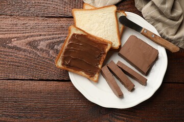 Sandwiches with chocolate butter and knife on wooden table, top view. Space for text