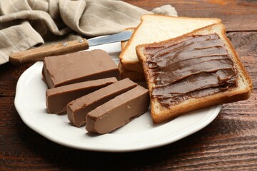 Sandwiches with chocolate butter and knife on wooden table, closeup