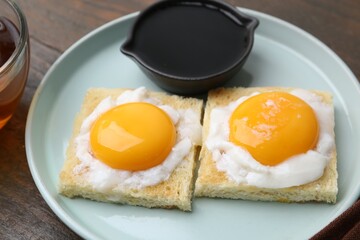 Tasty kaya toasts with half-boiled eggs served on wooden table, closeup. Traditional asian breakfast
