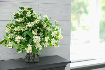 Beautiful jasmine flowers in vase fireplace indoors, space for text