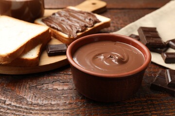 Tasty chocolate butter, pieces and bread on wooden table, closeup
