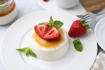 Tasty panna cotta with caramel, strawberries and mint on table, above view