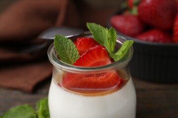 Tasty panna cotta with caramel, strawberries and mint on table, closeup
