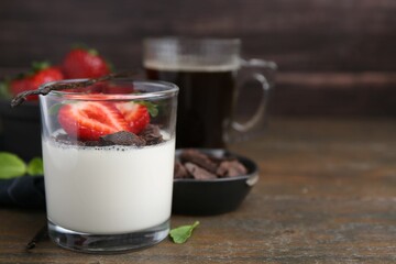 Tasty panna cotta with chocolate, strawberries, mint and vanilla pods on wooden table, closeup. Space for text