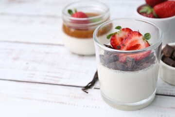 Tasty panna cotta with chocolate, strawberries and vanilla on white wooden table, closeup. Space for text