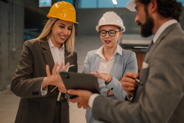 Engineers and architects discussing building plans on tablet in modern office