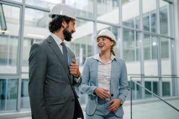 Smiling architects walking and talking about project in modern office building
