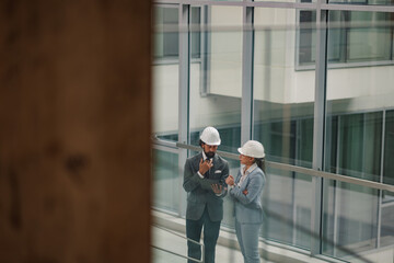 Architects discussing building plans using tablet in modern office building