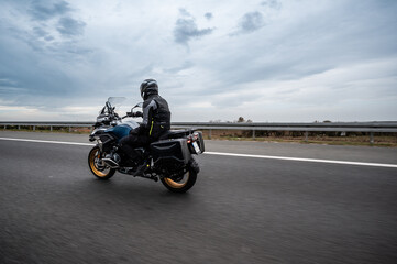 Motorcyclist riding on highway under cloudy sky