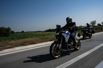 Bikers riding fast motorcycles on country road during summer day