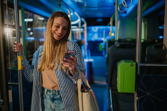 Young woman using smartphone on a moving bus at night