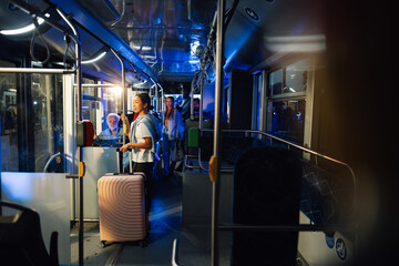Young woman traveling by bus at night with rolling suitcase © Zamrznuti tonovi