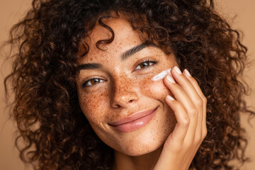 Young woman of African descent with curly black hair, light brown skin and freckles applying white cream to her face with fingers and looking at camera smiling. Healthy glowing skin. Generative AI
