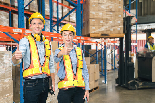 Confidence caucasian man, woman staff worker wear safety helmets, vest show teamwork collaborate, cooperation in logistics inventory operation. show success, efficiency in modern warehouse management. - Powered by Adobe