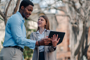 Business colleagues using tablet outdoors, discussing work
