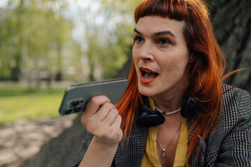 Businesswoman recording voice message using smartphone in park