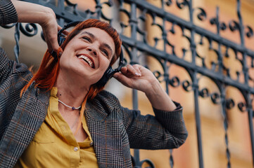 Happy businesswoman listening to music with headphones outdoors