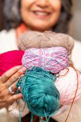 Senior woman holding colorful yarn balls for knitting