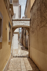Narrow stone alley with arch. Old European town Porec, Croatia.