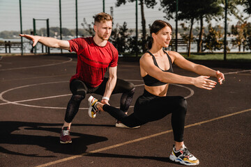 Fitness couple doing lunges on outdoor sports court during sunny day workout. Active lifestyle,...