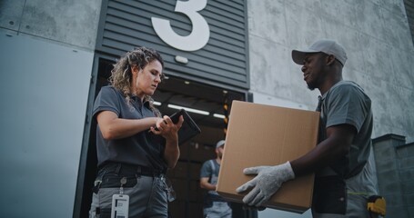 Multiethnic Workers Taking Cardboard Boxes with Online Orders, E-Commerce Goods to Logistics Retail Warehouse. Female Manager Scanning Parcels with Barcode Scanner, Using Tablet Computer. Slow Motion.