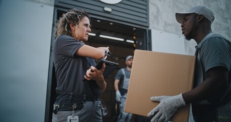 Multiethnic Workers Taking Cardboard Boxes with Online Orders, E-Commerce Goods to Logistics Retail Warehouse. Female Manager Scanning Parcels with Barcode Scanner, Using Tablet Computer. Slow Motion.