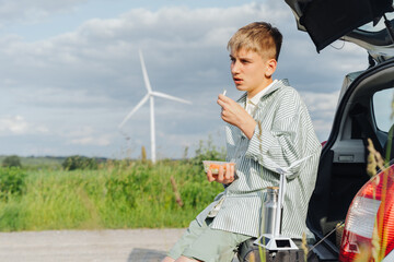 Boy with container snack and wind turbine in background