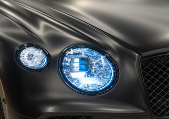 LED headlights of a modern and expensive black car, hood and radiator grille. Front LED headlight...