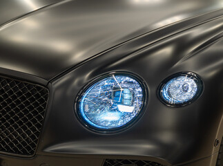 LED headlights of a modern and expensive black car, hood and radiator grille. Front LED headlight...