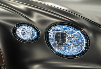 LED headlights of a modern and expensive black car, hood and radiator grille. Front LED headlight on a black SUV car. Matte black premium car LED headlights close-up. Modern sport car headlight. 