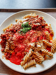pasta with Bolognese and tomato sauce, parmesan cheese and garnish, top down view, close up, vertical shot