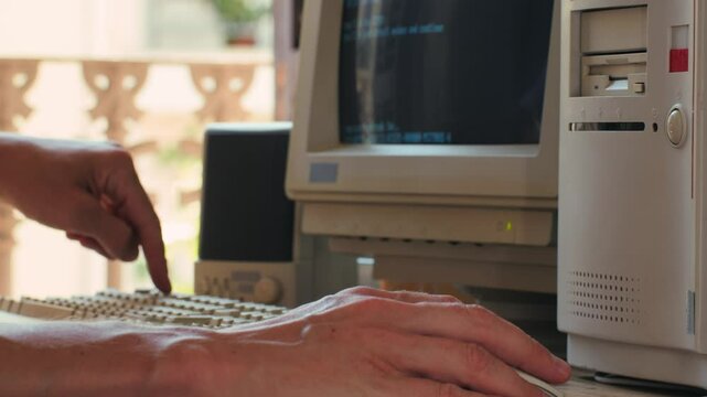 Man working and gaming on retro computer PC, IT engineer with vintage computer at home, using old fashion technology, close up of retro setup. 