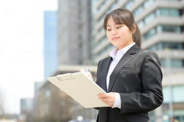 屋外でバインダーを持つ日本人女性