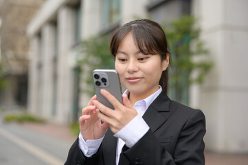 ビル街でスマホを見る日本人女性