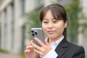 ビル街でスマホを見る日本人女性