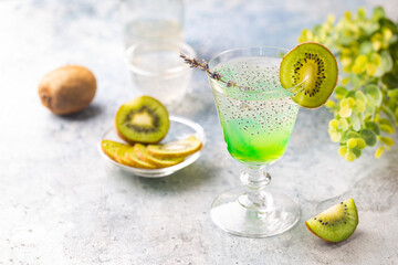 Cold cocktail kiwi drink in a glass with fresh fruits on gray background