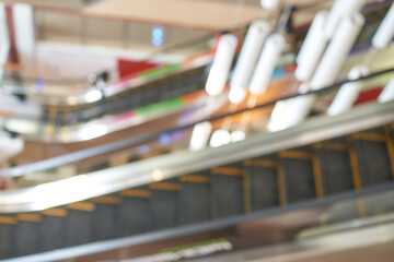 Abstract blurred view of modern shopping mall escalators with colorful background.