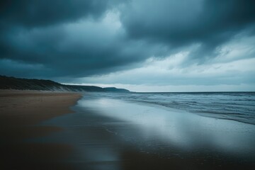 Obraz premium A dramatic coastal scene at twilight. Dark, brooding clouds gather over a beach, casting a moody atmosphere. Gentle waves lap the shore, and the sand reflects the muted light. 