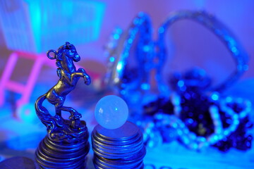 A statuette of a horse with coins and a crystal ball. Financial horoscope.