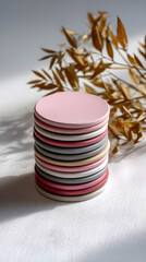 Stacked round coasters in pastel colors with dried foliage and soft shadows