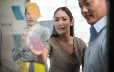 Asian business team in a creative meeting, collaborating and sharing ideas using colorful notes on...