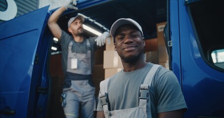 Naklejka premium Portrait of Multiethnic Workers in Uniform Standing Outside of Logistics Retail Warehouse, Smiling and Looking at Camera. Delivery Truck Full of Cardboard Boxes with E-Commerce Products for Shipment.