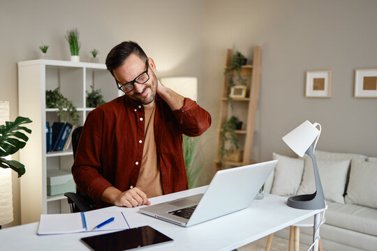 Man experiencing neck pain while working at desk