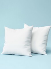 Two white square pillows on light blue background